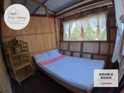 a bed in a wooden room with a window at Cafe Sabang Guest House in Sabang