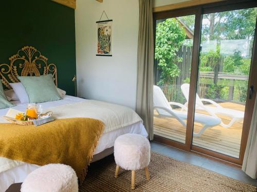 a bedroom with a bed with two chairs and a patio at Cabaña Romántica in Cunco