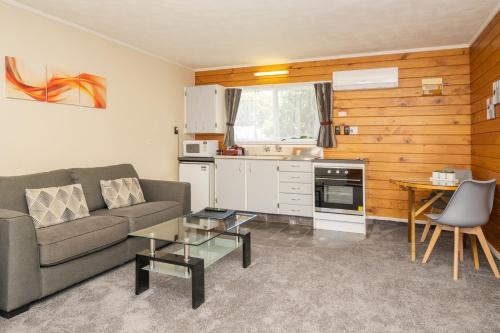 uma sala de estar com um sofá e uma mesa em Tudor Park Motel em Gisborne