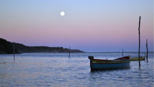 two boats in the water with the moon in the sky at Recanto das Amendoeiras in Guarda do Embaú