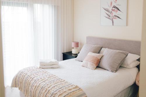 a bedroom with a bed with white sheets and pillows at Exclusive Anglesea River Beach Apartment in Anglesea