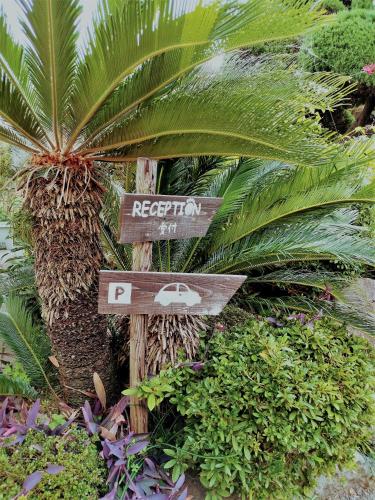 un cartello per un resort con palme e piante di Happy Neko a Beppu