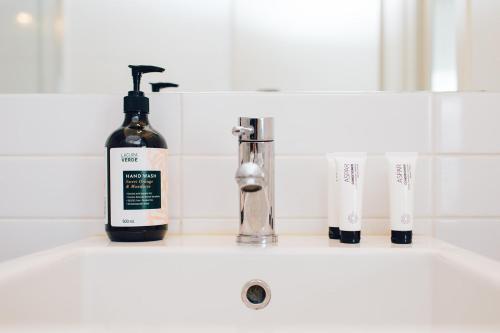 a bathroom sink with a bottle of soap and toothbrushes at Exclusive Anglesea River Beach Apartment in Anglesea