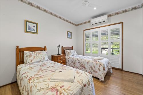 a bedroom with two beds and a window at Birds 'n' Bloom Cottages in Yungaburra