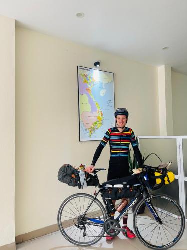 a man is standing next to a bike at Phúc Đức Hotel in Thanh Hóa