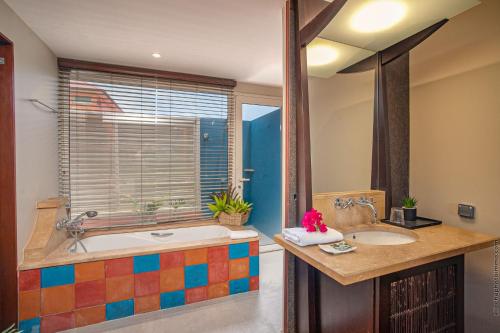 a bathroom with two sinks and a tub with a window at Villa Maorie 5 chambres avec piscine privée in Le François