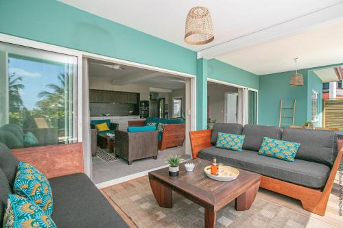 ein Wohnzimmer mit einem Sofa und einem Tisch in der Unterkunft Villa Maorie 5 chambres avec piscine privée in Le François