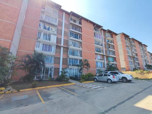 un gran edificio de apartamentos con dos coches aparcados en un aparcamiento en Apartamento frente al Aeropuerto de Maiquetía en Maiquetía