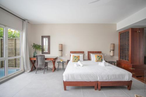 a white bedroom with a bed and a desk at Villa Maorie 5 chambres avec piscine privée in Le François