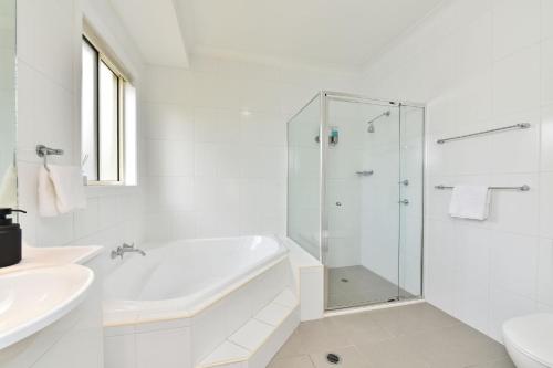 ein weißes Bad mit einer Dusche und einem Waschbecken in der Unterkunft The Ponderosa on Merewether in Rothbury