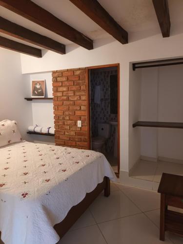 - une chambre avec un lit et un mur en briques dans l'établissement Cemandy Hostal, à Villa de Leyva