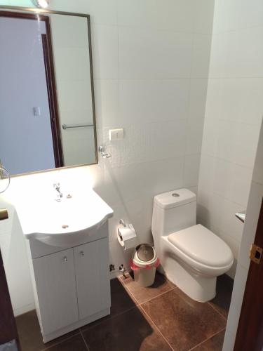 a bathroom with a toilet and a sink and a mirror at CASA PREMIUM Estadio Carlos Dittborn in Arica