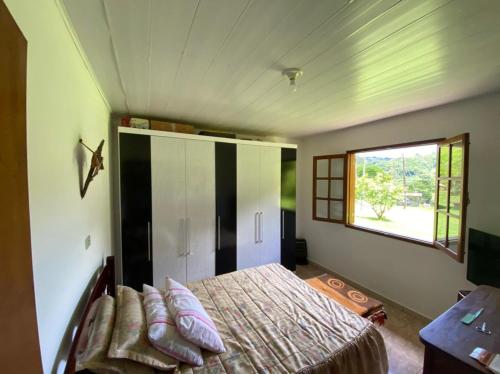1 dormitorio con cama y ventana en Chácara Santo Antônio, en Santo Antônio do Pinhal