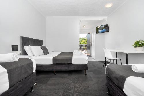 a bedroom with two beds and a table and a desk at The Robert Towns in Townsville