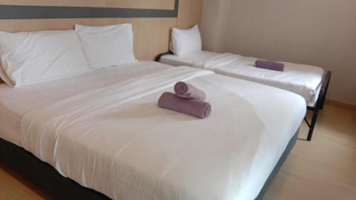 two beds with white sheets and a purple pillow on them at Double Story in the Sky - Genting Windmill Duplex Suite in Genting Highlands
