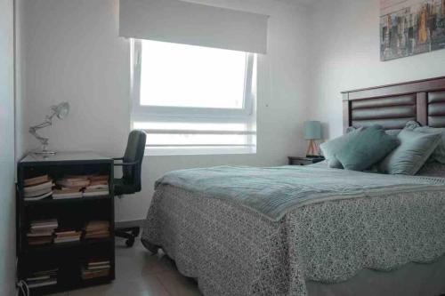 ein Schlafzimmer mit einem Bett, einem Stuhl und einem Fenster in der Unterkunft Apartamento con vista al mar en Viña-Valparaiso in Valparaíso