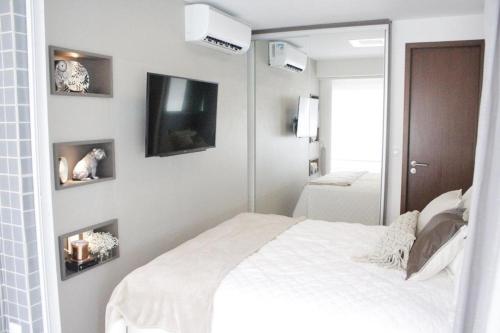 a bedroom with a white bed and a mirror at LIV INN Apartamento na Beira-Mar Fortaleza in Fortaleza