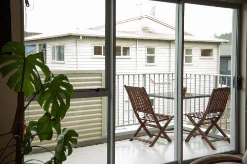 two chairs on a balcony looking out at a house at Oceans 15 - Self-service Apartments in Whitianga