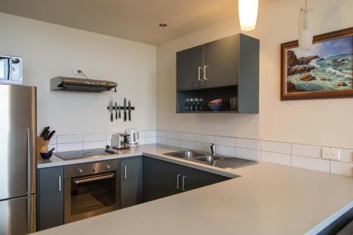 a kitchen with black cabinets and a stainless steel refrigerator at Oceans 15 - Self-service Apartments in Whitianga