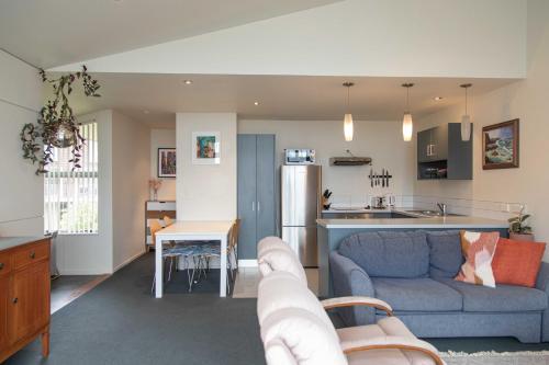 a living room with a blue couch and a kitchen at Oceans 15 - Self-service Apartments in Whitianga