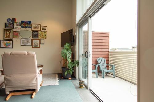 a living room with a chair and a sliding glass door at Oceans 15 - Self-service Apartments in Whitianga