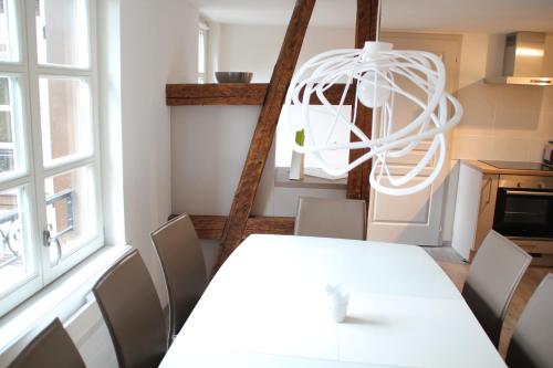 une salle à manger avec une table et des chaises blanches dans l'établissement A L'ill - Apparts & Studios Strasbourg Hyper Centre, à Strasbourg