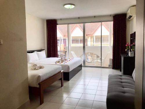 a hotel room with two beds and a balcony at Kata Beach Guesthouse in Kata Beach