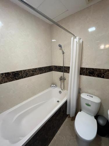 a bathroom with a white tub and a toilet and a sink at Mango Hotel - Ha Noi Railway station in Hanoi