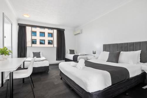 a hotel room with two beds and a table and chairs at The Robert Towns in Townsville