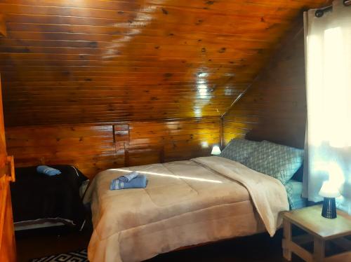 a bedroom with a bed and a wooden wall at Cabana Alto do Monte in Gramado