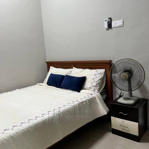 a bed with a blue pillow and a fan at Homestay Ayer Keroh Tasik Utama in Ayer Keroh