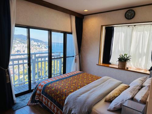 a bedroom with a bed and a large window at 熱海天海ヴィラ/ Atami Tenkai Villa in Atami