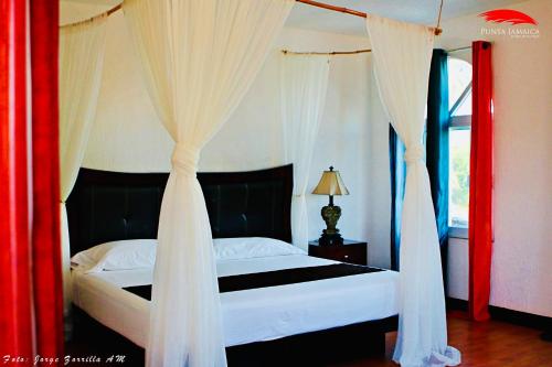 Schlafzimmer mit einem Bett mit Vorhängen und einem Fenster in der Unterkunft Hotel Boutique Punta Jamaica in Acapulco
