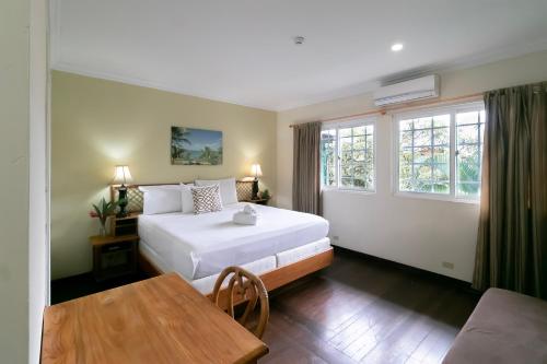 um quarto com uma cama, uma mesa e janelas em Gran Hotel Bahia em Bocas del Toro