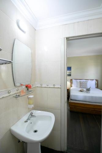 a bathroom with a sink and a bed with a mirror at Gran Hotel Bahia in Bocas del Toro
