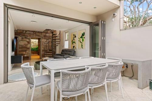 a dining room with a white table and chairs at Panorama Firework View - Classic 4-Level Terrace Style Living in Kirribilli !!! in Sydney