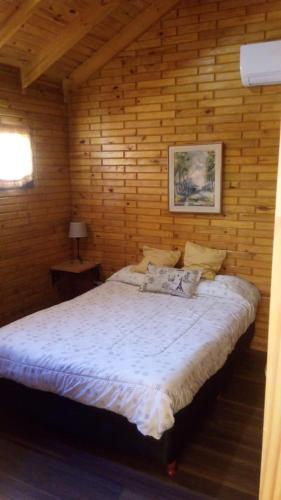 a bedroom with a bed in a wooden wall at Cabañas El Druida in Villa General Belgrano