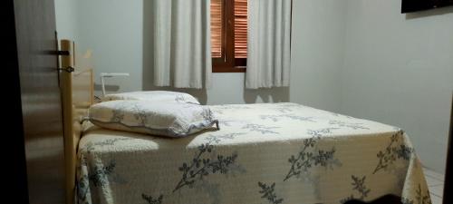 a bed with two pillows on it in a room at Casa agradável, ampla com estacionamento in Tramandaí