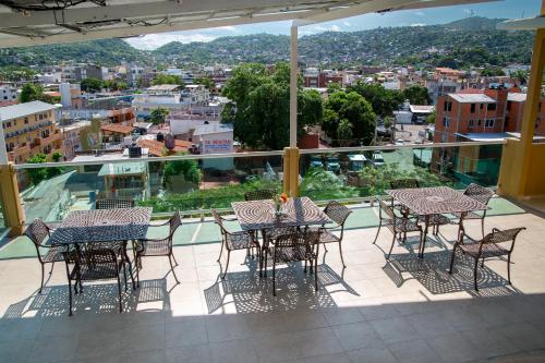 a balcony with tables and chairs and a view of a city at Fabuloso Hotel Las Vegas in Zihuatanejo