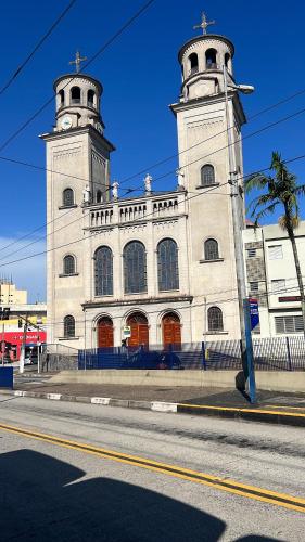 a large white building with two towers on a street at Hotel City II in Santo André