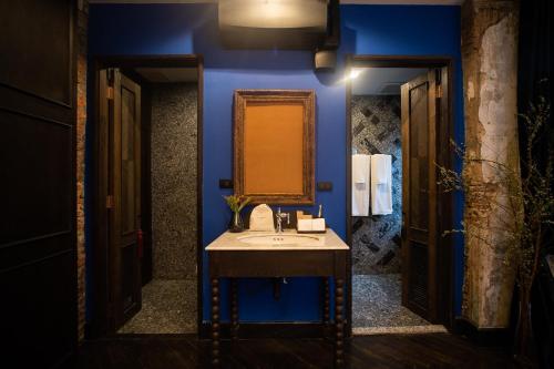 a blue bathroom with a sink and a mirror at Baan Tuk Din Hotel in Bangkok