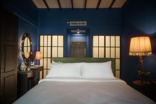 sypialnia z dużym białym łóżkiem i niebieskimi ścianami w obiekcie Baan Tuk Din Hotel w mieście Bangkok