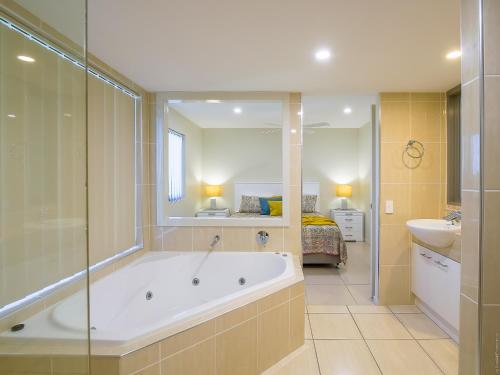a bathroom with a tub and a sink and a bed at Pier View Serenity in Urangan