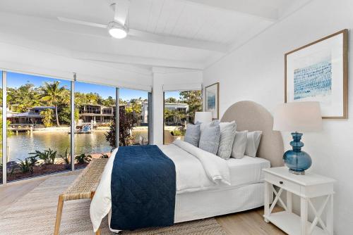 a white bedroom with a large bed and large windows at Edgewater Collection by Stay Noosa in Noosa Heads