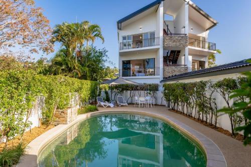 an apartment building with a swimming pool in front of a house at Edgewater Collection by Stay Noosa in Noosa Heads