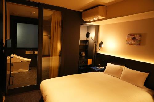 東京にあるNplus HOTEL 東神田秋葉原のベッドとテレビが備わるホテルルームです。