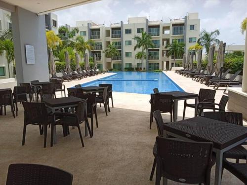 a patio with tables and chairs next to a swimming pool at Cancun Lucky & Friendly Condo in Cancún