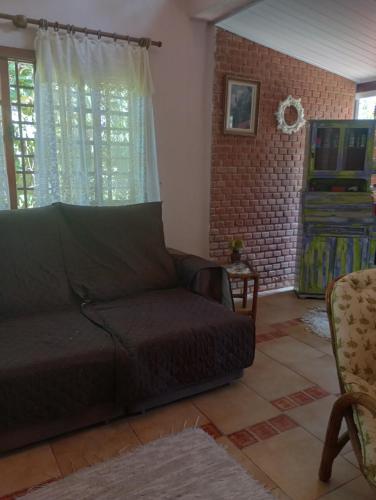 a living room with a couch and a brick wall at Casa da Roseli - Pitangueiras in Guarujá