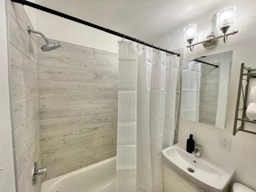 La salle de bains blanche est pourvue d'une douche, d'une baignoire et d'un lavabo. dans l'établissement The Clemente Mt. Washington by Luxe PGH, à Pittsburgh