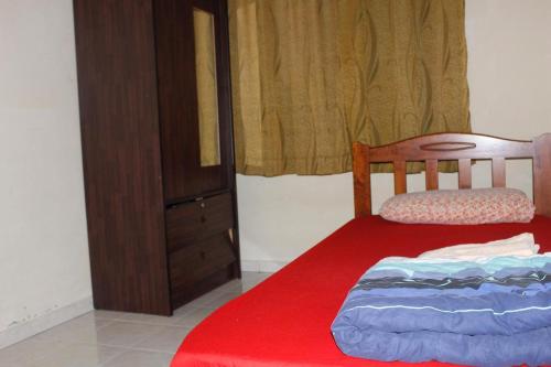 a bedroom with a red bed and a dresser at Homestay Mokde in Muar